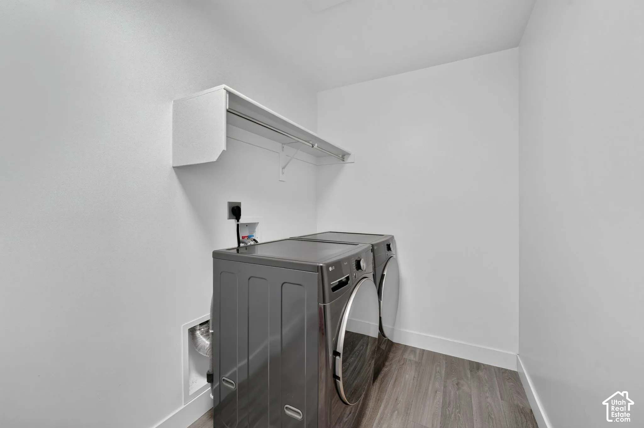 Laundry area featuring wood-finish flooring and integrated wall-mounted shelving