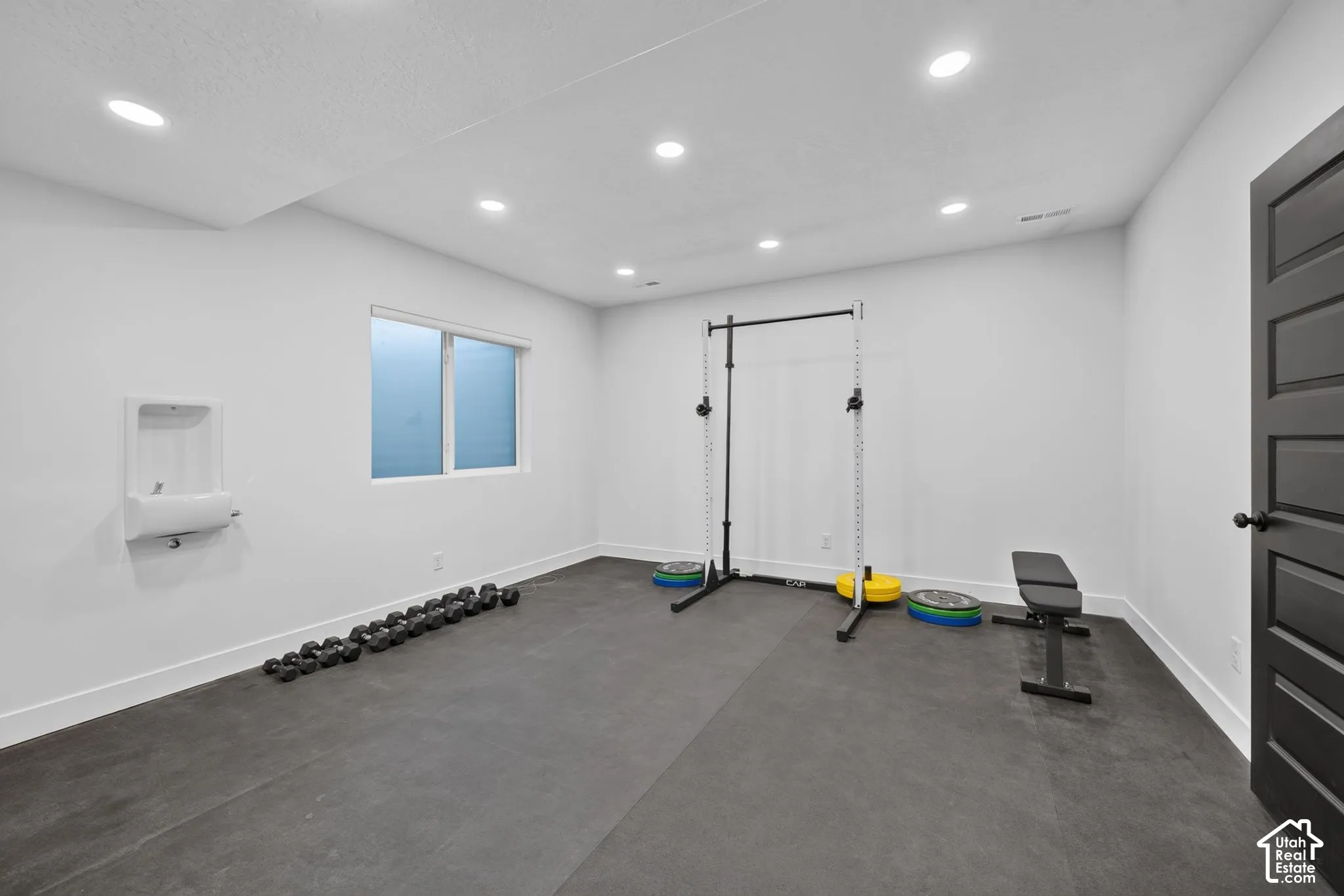 Room featuring recessed lighting, a single window, and a wall-mounted drinking fountain, finished with dark rubberized flooring and a five-panel interior door