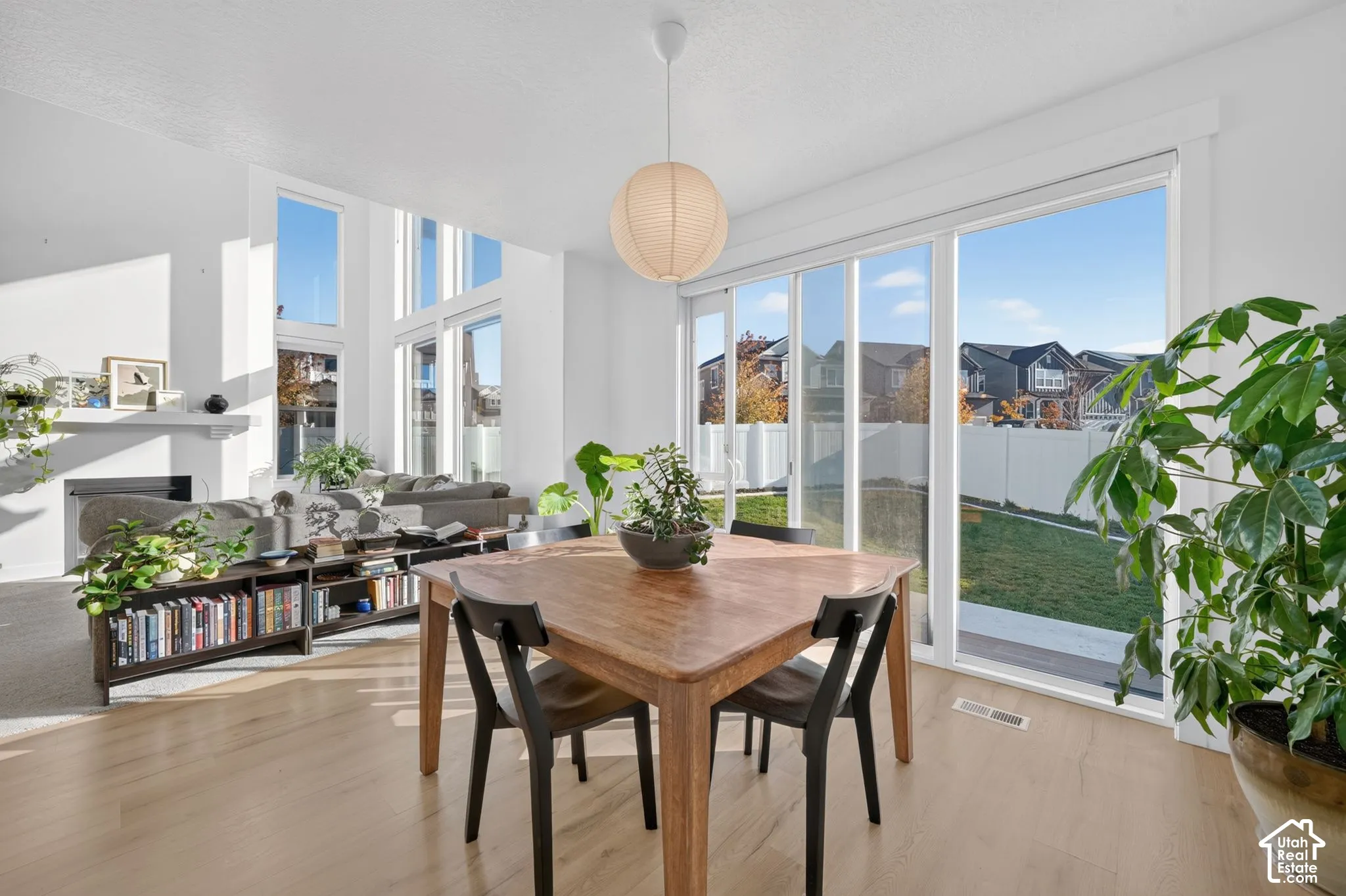 Open-concept interior featuring floor-to-ceiling windows, wood-finish flooring, a contemporary sphere pendant light, and sliding glass doors