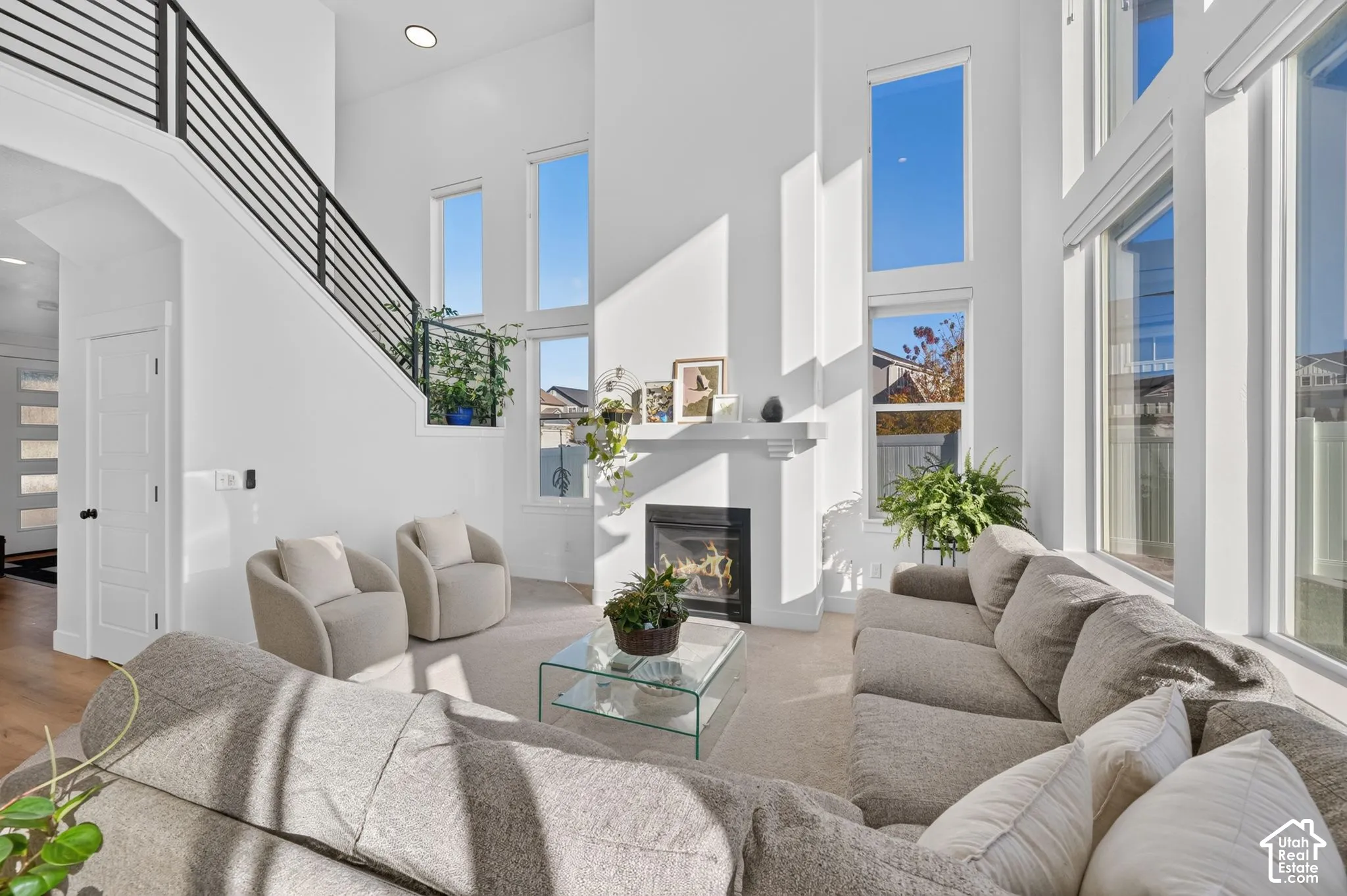 High ceilings featuring stacked windows, fireplace with a decorative mantel, and staircase with horizontal metal railing