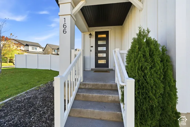 Covered entryway featuring vertical siding, concrete steps with white railing, and a multi-panel door with glass inserts