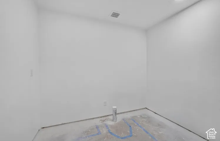Interior space featuring white walls, concrete flooring, and exposed plumbing infrastructure