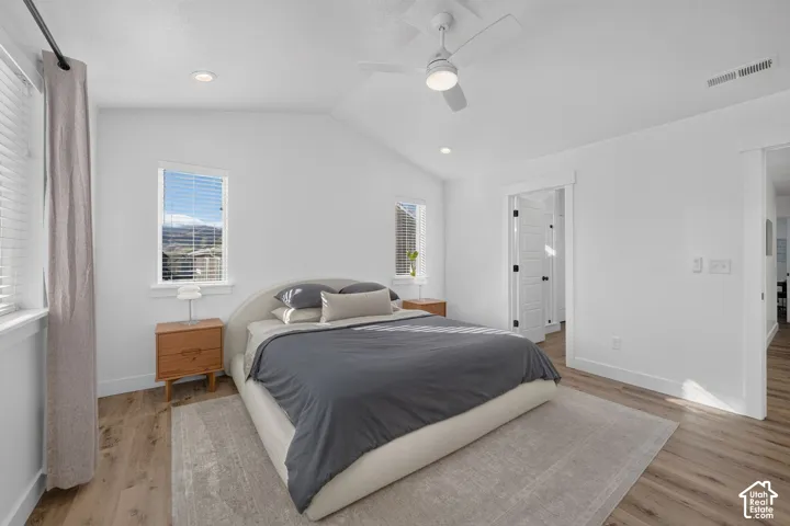 Vaulted ceilings, wood-finish flooring, recessed lighting, and a white ceiling fan with an integrated light fixture