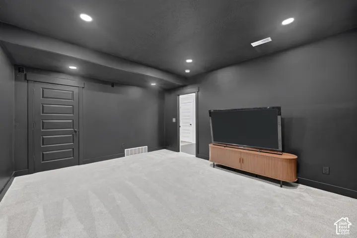 Interior space featuring dark-toned walls and trim, recessed ceiling lighting, light-colored carpeting, and a five-panel interior door