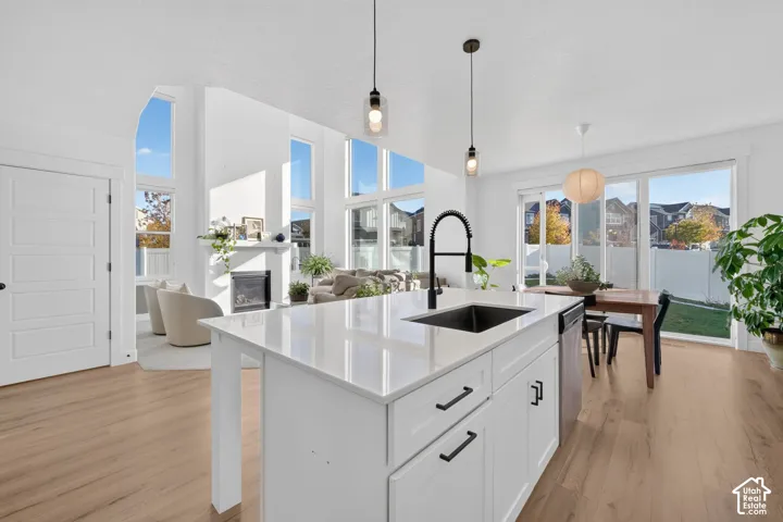 Kitchen island with a quartz countertop, under-mount sink, and matte black faucet, complemented by wood-finish flooring, floor-to-ceiling windows, and a built-in fireplace