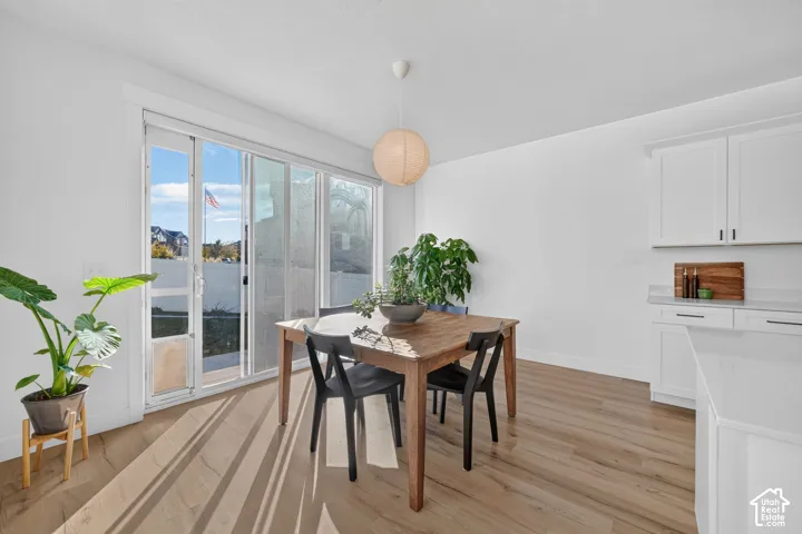Wood-finish flooring, white shaker-style cabinetry, solid-surface countertops, and sliding glass doors providing access to the exterior