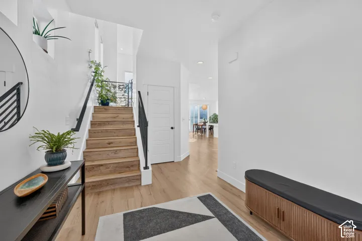 Staircase featuring wood-finish treads and black metal railing, wood-finish flooring, and recessed ceiling lighting