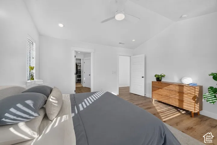 Room featuring wood-finish flooring, vaulted ceilings, recessed lighting, and a white ceiling fan