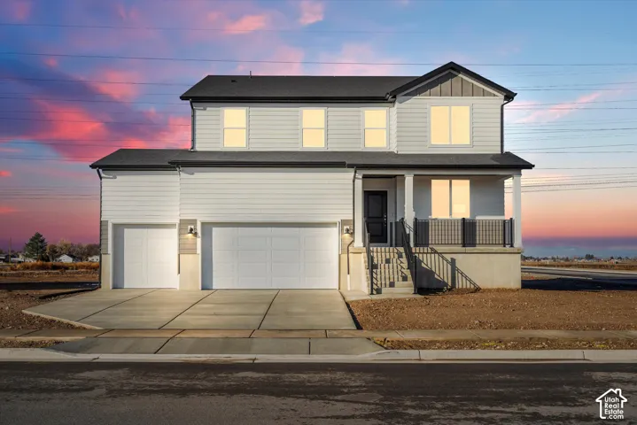 Two-story residence featuring horizontal lap siding, a three-car garage, a covered front porch with metal railing, and a concrete driveway
