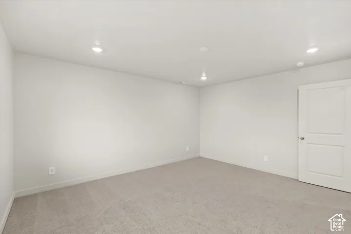 Neutral-toned room with plush carpeting, recessed lighting, and a two-panel interior door