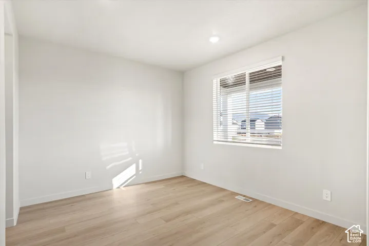 Neutral interior space featuring wood-finish flooring, crisp white walls, and a recessed ceiling light