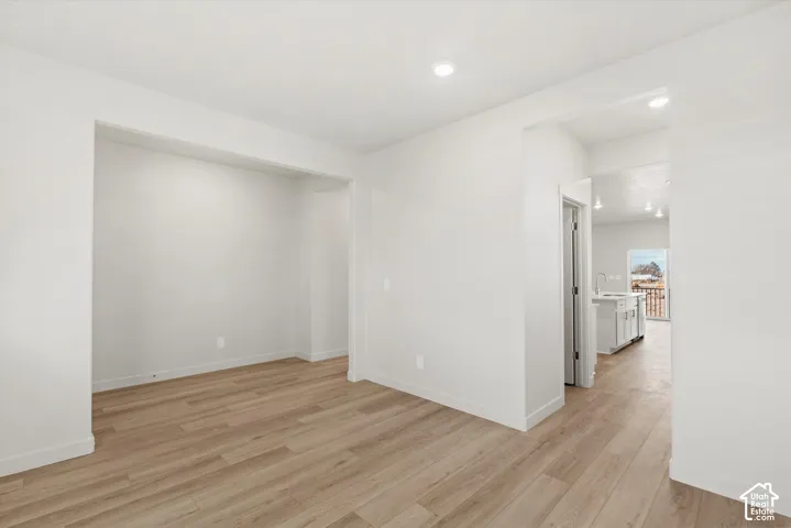Neutral-toned interior space featuring wood-finish flooring, crisp white walls, and recessed ceiling lighting