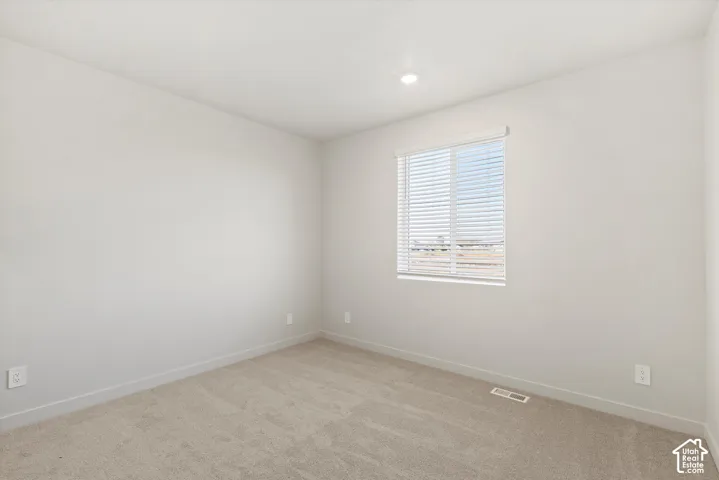 Neutral wall tones, wall-to-wall carpeting, and horizontal window blinds with a single-pane window