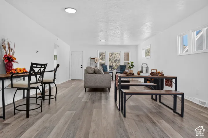 Open-concept interior featuring wood-finish flooring, neutral walls, recessed lighting, and large windows with natural illumination