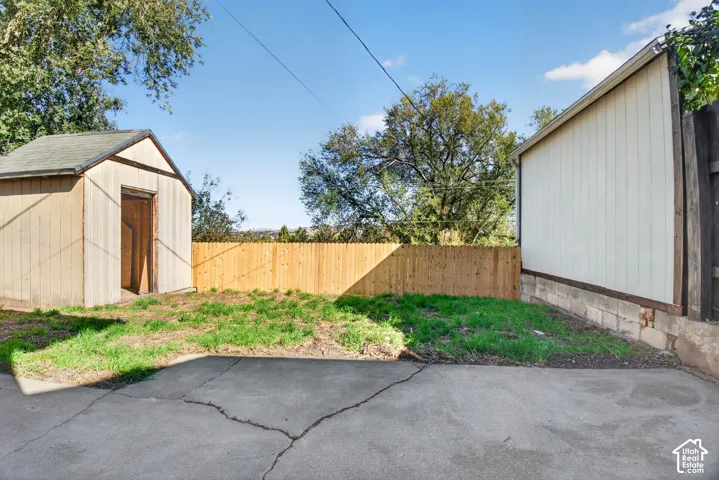 Exterior area featuring a concrete patio, wood-style storage shed, and wood perimeter fencing