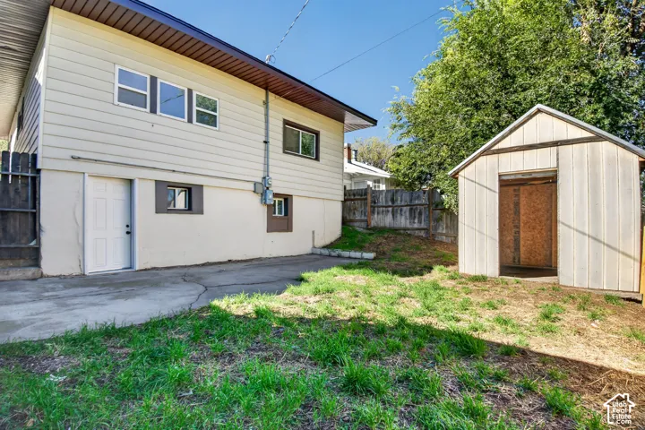 Exterior space featuring horizontal siding, a concrete patio, a detached storage shed, and perimeter wood fencing