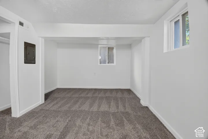 Room featuring neutral wall-to-wall carpeting, two sliding windows, and a built-in closet with an integrated electrical panel