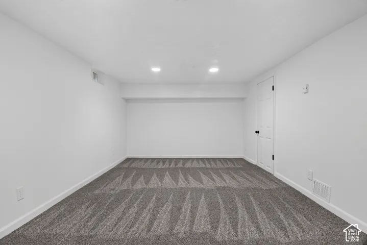 Interior room featuring patterned wall-to-wall carpeting, recessed ceiling lighting, a six-panel interior door, and a high-set casement window