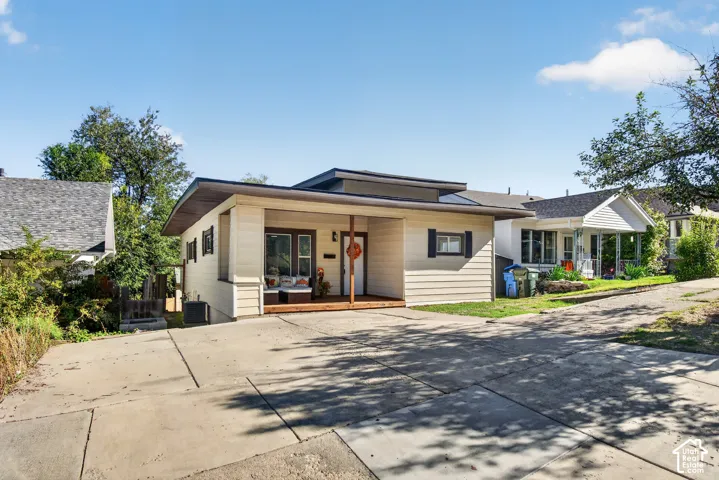 Single-story residence with horizontal siding, a low-pitch roofline, a covered front porch with wood decking, and a concrete driveway