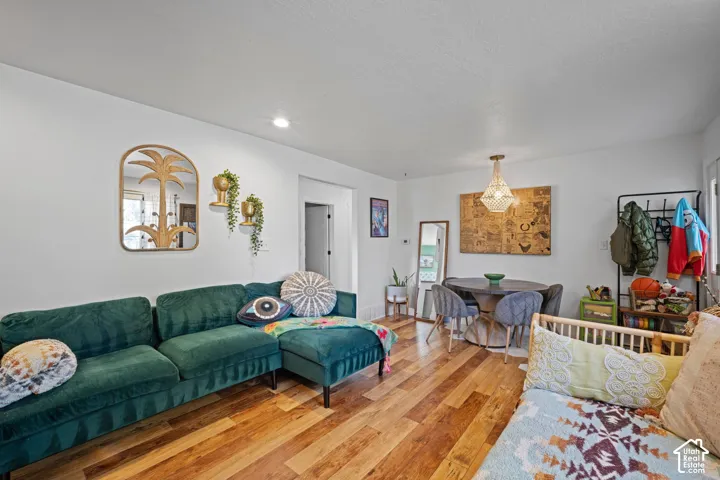 Interior room featuring wood-finish flooring, smooth white walls, white ceilings with a recessed light, and a hanging pendant light fixture