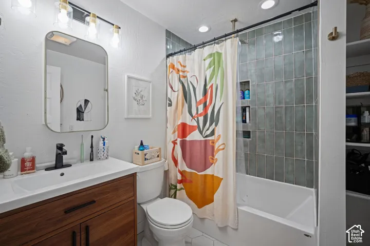 Bathroom featuring a wood-finish vanity with a white countertop, matte black faucet, vertical blue-grey shower tile with a built-in niche, and hexagonal floor tile