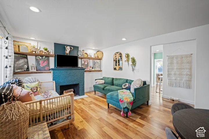 Living area featuring wood-finish flooring, recessed lighting, and a floor-to-ceiling fireplace surround with built-in natural wood shelving