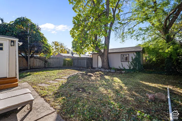 Backyard featuring a stone paver walkway, wood-style privacy fencing, and an exterior storage structure