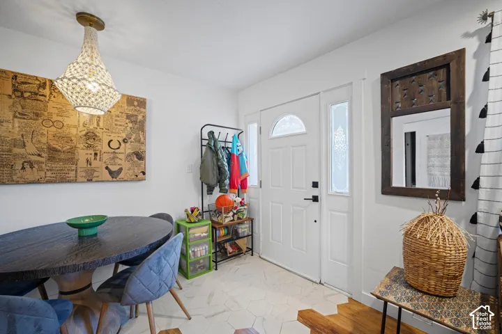 Entryway featuring a white exterior door with glass sidelights, hexagon tile flooring, and a decorative pendant light fixture