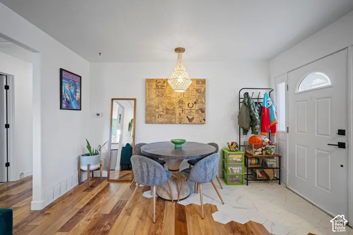 Entry area featuring wood-finish flooring, white hexagonal tile inlay, and a central tiered pendant light fixture