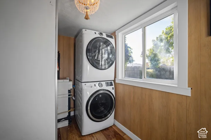 Utility area featuring wood-finish wall paneling, wood-finish flooring, a slider window, and a decorative bead-style light fixture