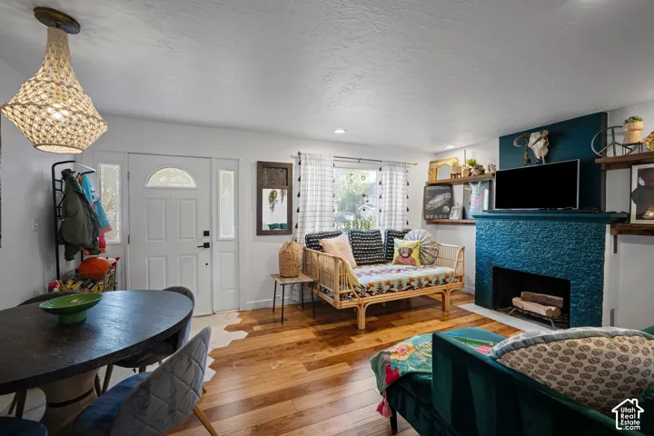 Living space featuring wood-finish flooring, a textured stone fireplace surround, custom built-in shelving, and a decorative woven light fixture