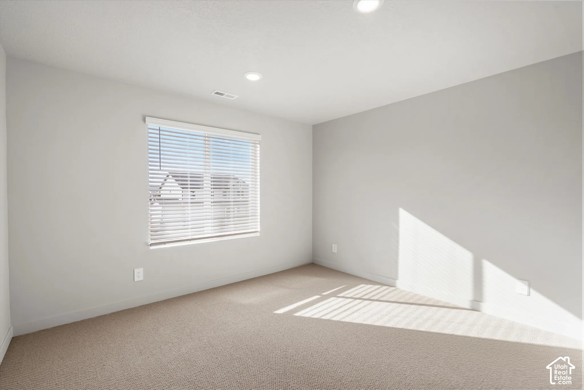 *DISCLAIMER* Interior color package may vary. Neutral-toned interior space featuring light-colored wall-to-wall carpeting, inset recessed lighting, and a single-pane window with installed horizontal blinds