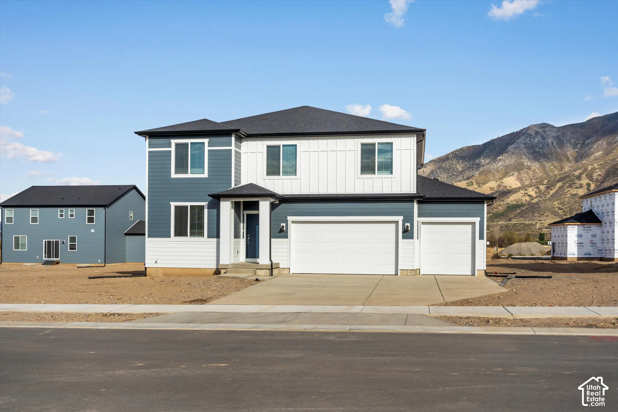 **DISCLAIMER** Elevation and exterior colors may vary. Two-story exterior featuring a mix of horizontal lap and vertical board-and-batten siding, a three-car garage, and a mountain backdrop