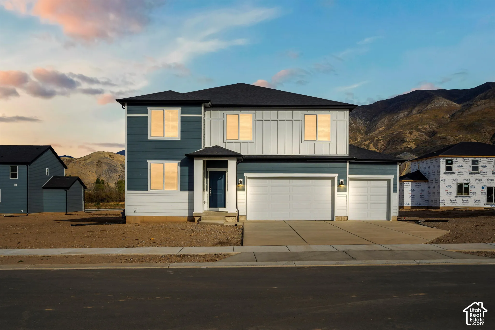 **DISCLAIMER** Elevation and exterior colors may vary. Two-story exterior featuring a mix of horizontal lap and vertical board-and-batten siding, a three-car garage, and mountain backdrop