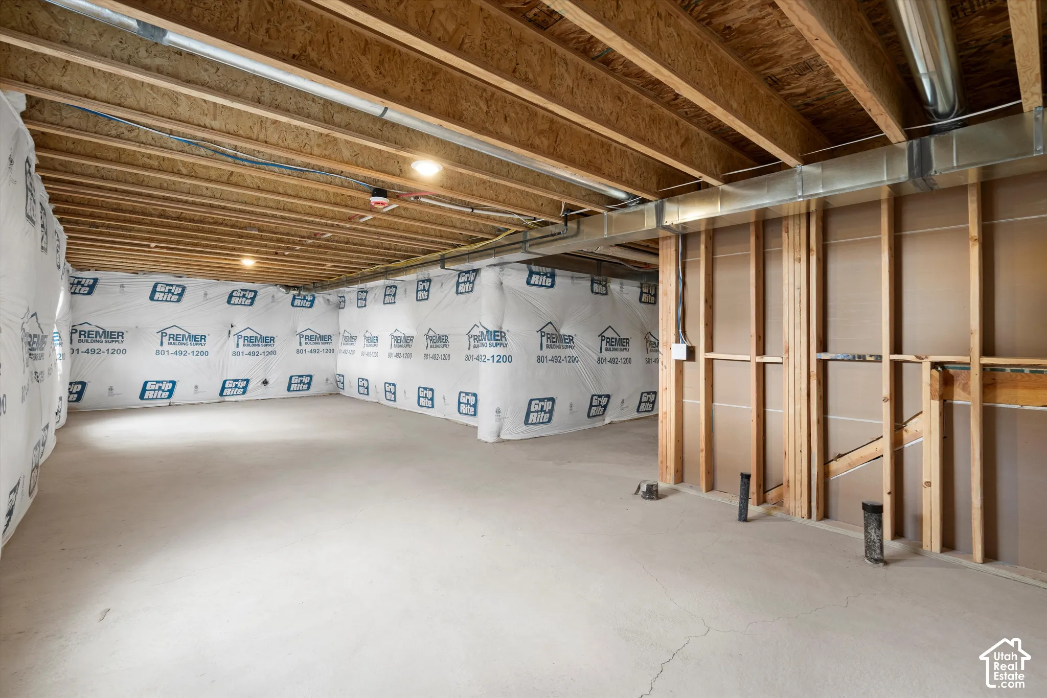 Unfinished basement level featuring an exposed wood-joist ceiling, concrete flooring, exterior-wall vapor barriers, and exposed wall framing
