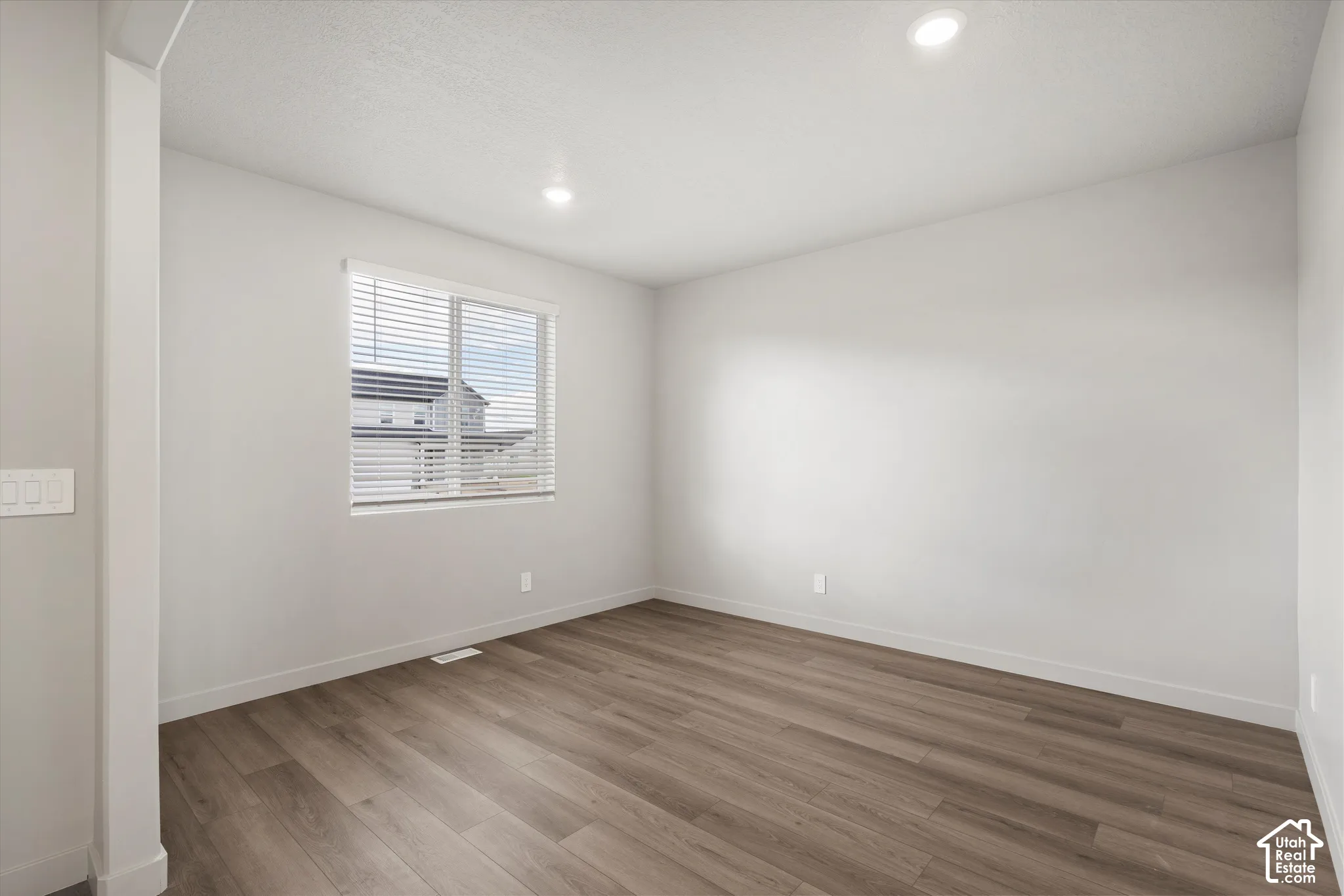*DISCLAIMER* Interior color package may vary. Room interior featuring wood-finish flooring, neutral wall tones, recessed lighting, and a window with horizontal blinds
