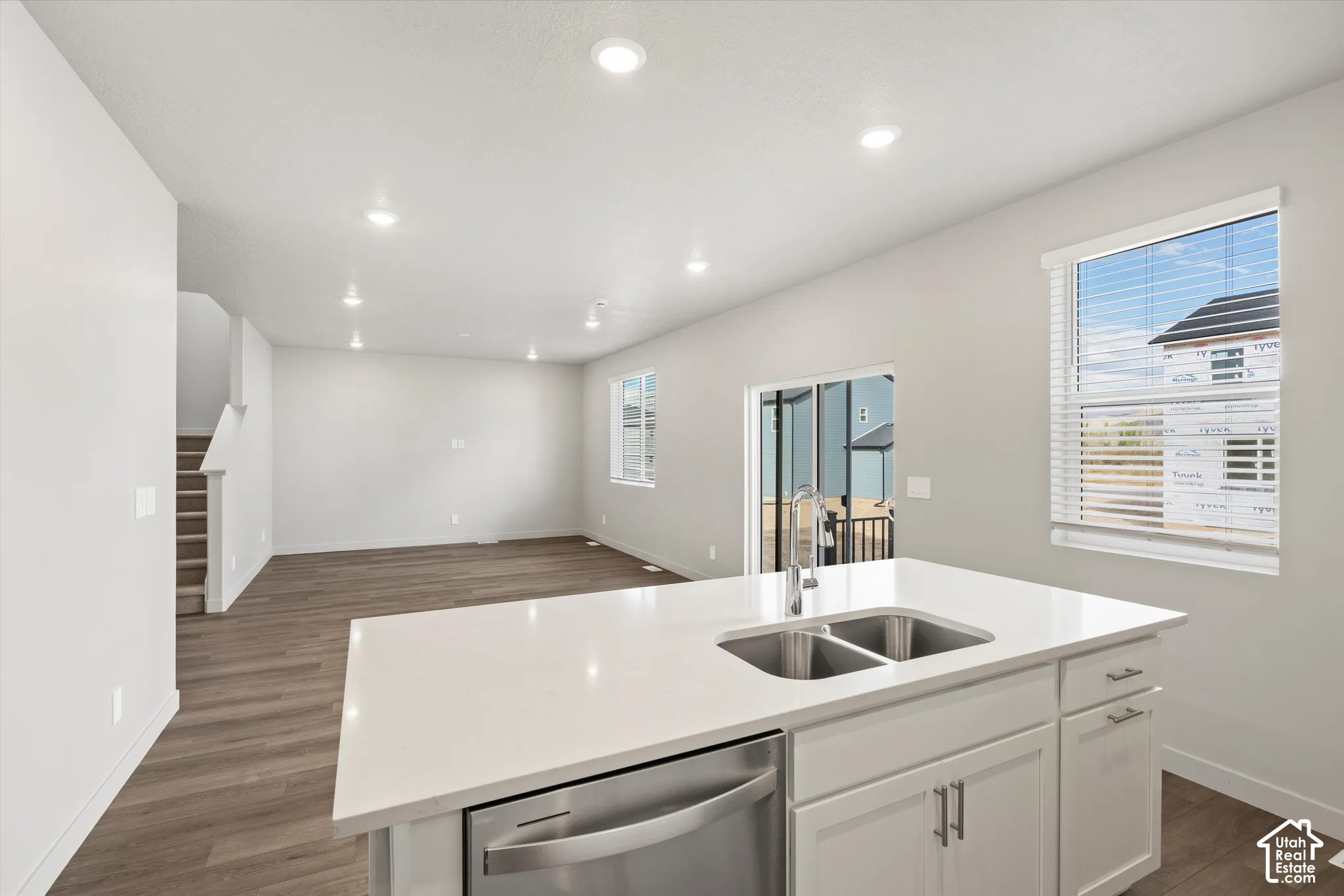 *DISCLAIMER* Interior color package may vary. Kitchen island featuring a solid-surface countertop, dual-basin stainless steel sink, and shaker-style cabinetry with matte metal hardware