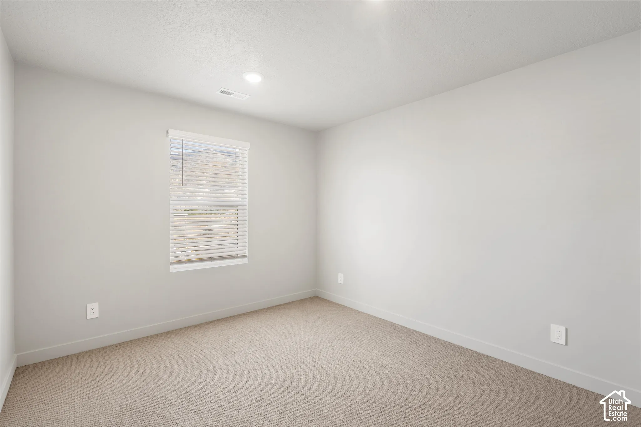 *DISCLAIMER* Interior color package may vary. Neutral wall finishes, recessed lighting, and wall-to-wall carpeting complemented by a window with adjustable blinds