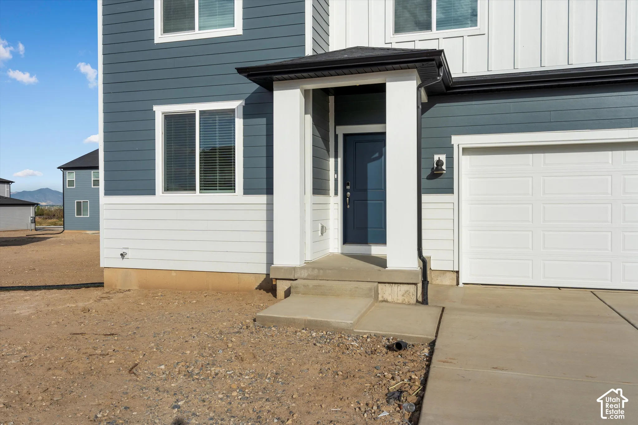 **DISCLAIMER** Elevation and exterior colors may vary. Multi-material exterior featuring horizontal lap siding, vertical board-and-batten siding, a covered entryway with square columns, and a concrete driveway