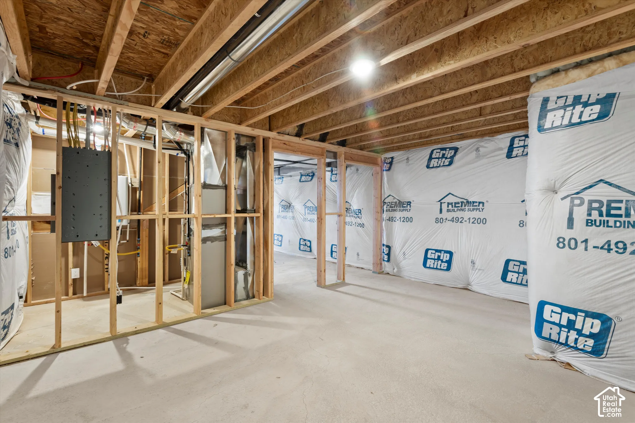 Unfinished basement featuring exposed wood-frame walls, concrete flooring, exposed ceiling joists, vapor-barrier insulation, and a mechanical area with a central HVAC unit