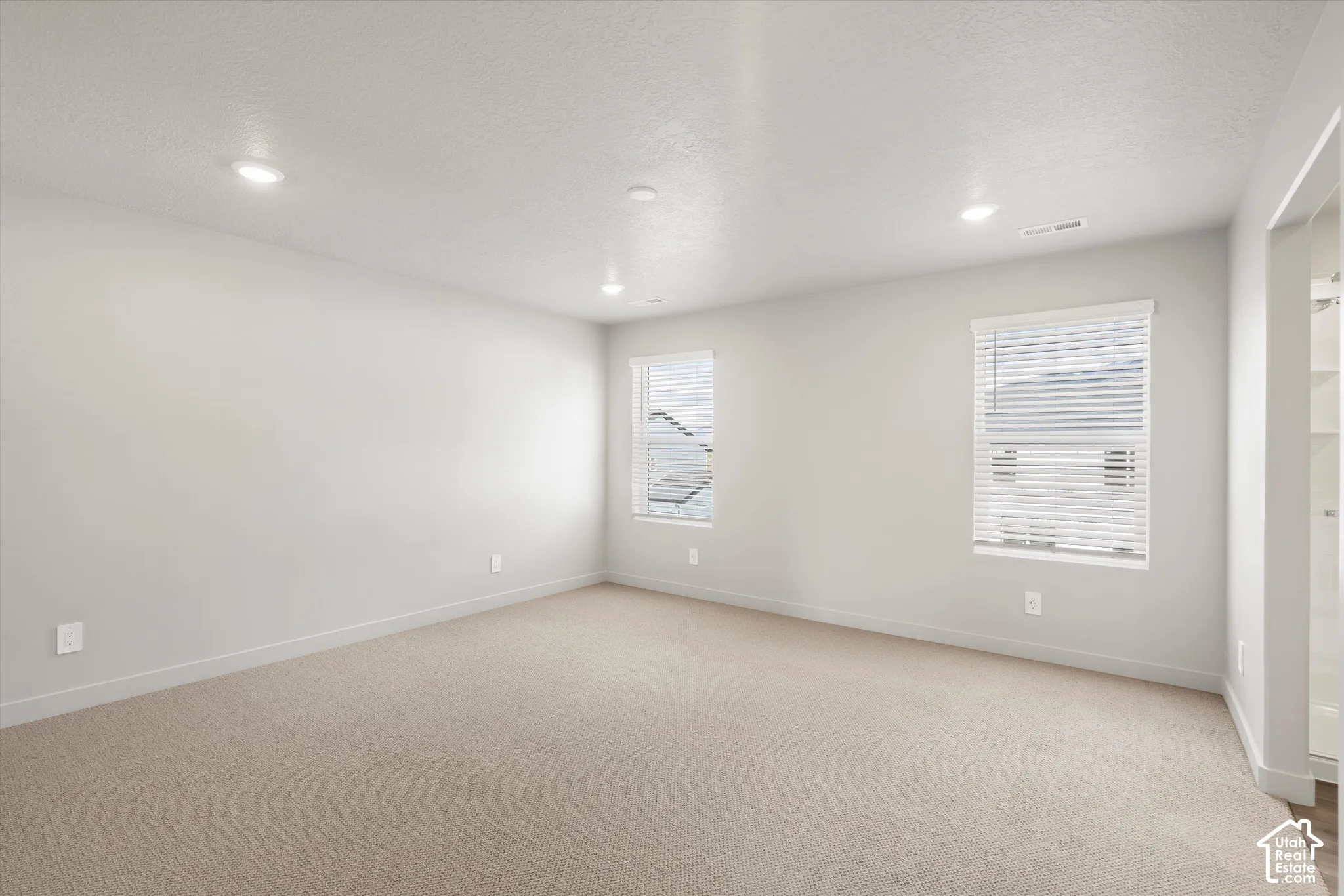 *DISCLAIMER* Interior color package may vary. Neutral-toned interior space featuring wall-to-wall carpeting, recessed ceiling lighting, and dual windows equipped with horizontal blinds