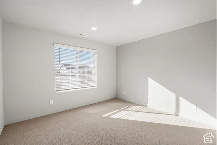 *DISCLAIMER* Interior color package may vary. Neutral-toned interior space featuring light-colored wall-to-wall carpeting, inset recessed lighting, and a single-pane window with installed horizontal blinds