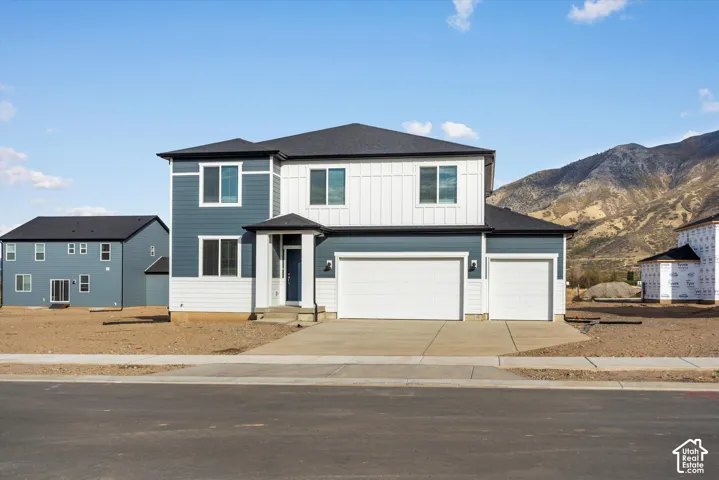 **DISCLAIMER** Elevation and exterior colors may vary. Two-story exterior featuring a mix of horizontal lap and vertical board-and-batten siding, a three-car garage, and a mountain backdrop
