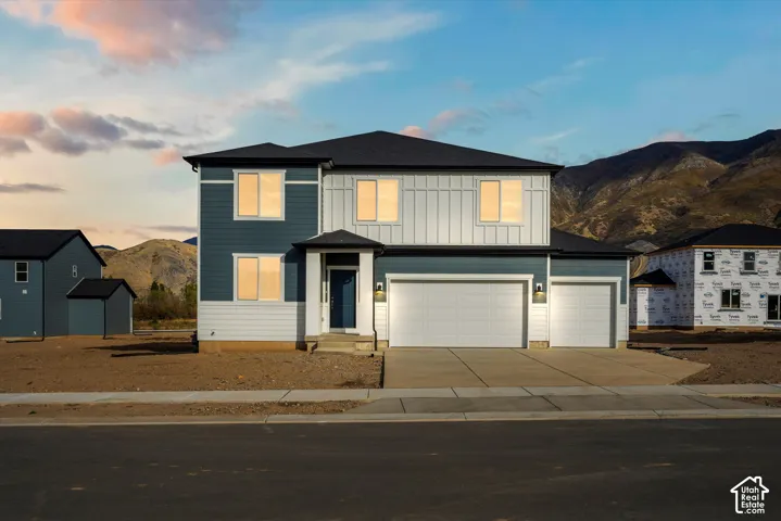 **DISCLAIMER** Elevation and exterior colors may vary. Two-story exterior featuring a mix of horizontal lap and vertical board-and-batten siding, a three-car garage, and mountain backdrop