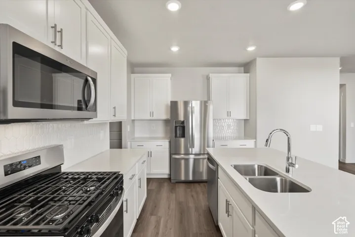 *DISCLAIMER* Interior color package may vary. Kitchen featuring white shaker-style cabinetry, stainless steel appliances, quartz countertops, a central island with an undermount double-basin sink, and recessed lighting