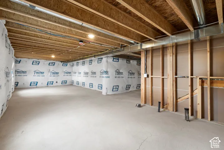 Unfinished basement level featuring an exposed wood-joist ceiling, concrete flooring, exterior-wall vapor barriers, and exposed wall framing