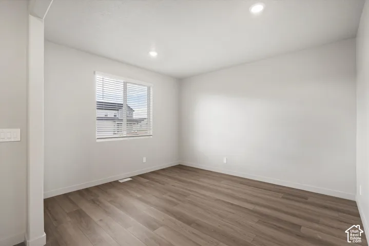 *DISCLAIMER* Interior color package may vary. Room interior featuring wood-finish flooring, neutral wall tones, recessed lighting, and a window with horizontal blinds