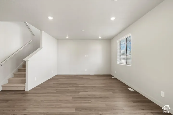 *DISCLAIMER* Interior color package may vary. Open-concept interior featuring neutral wall tones, wood-finish flooring, recessed lighting, carpeted stairs with a white handrail, and a window with horizontal blinds