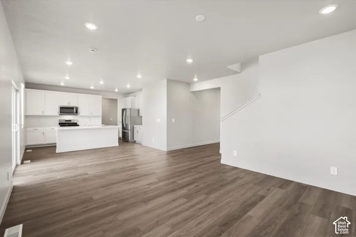 *DISCLAIMER* Interior color package may vary. Open-concept interior featuring wood-finish flooring, white cabinetry, recessed lighting, and a central kitchen island