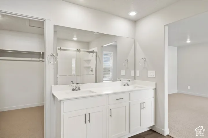 *DISCLAIMER* Interior color package may vary. Double vanity with white cabinetry, rectangular under-mount sinks, and solid surface countertops featuring a full-width mirror and polished chrome hardware